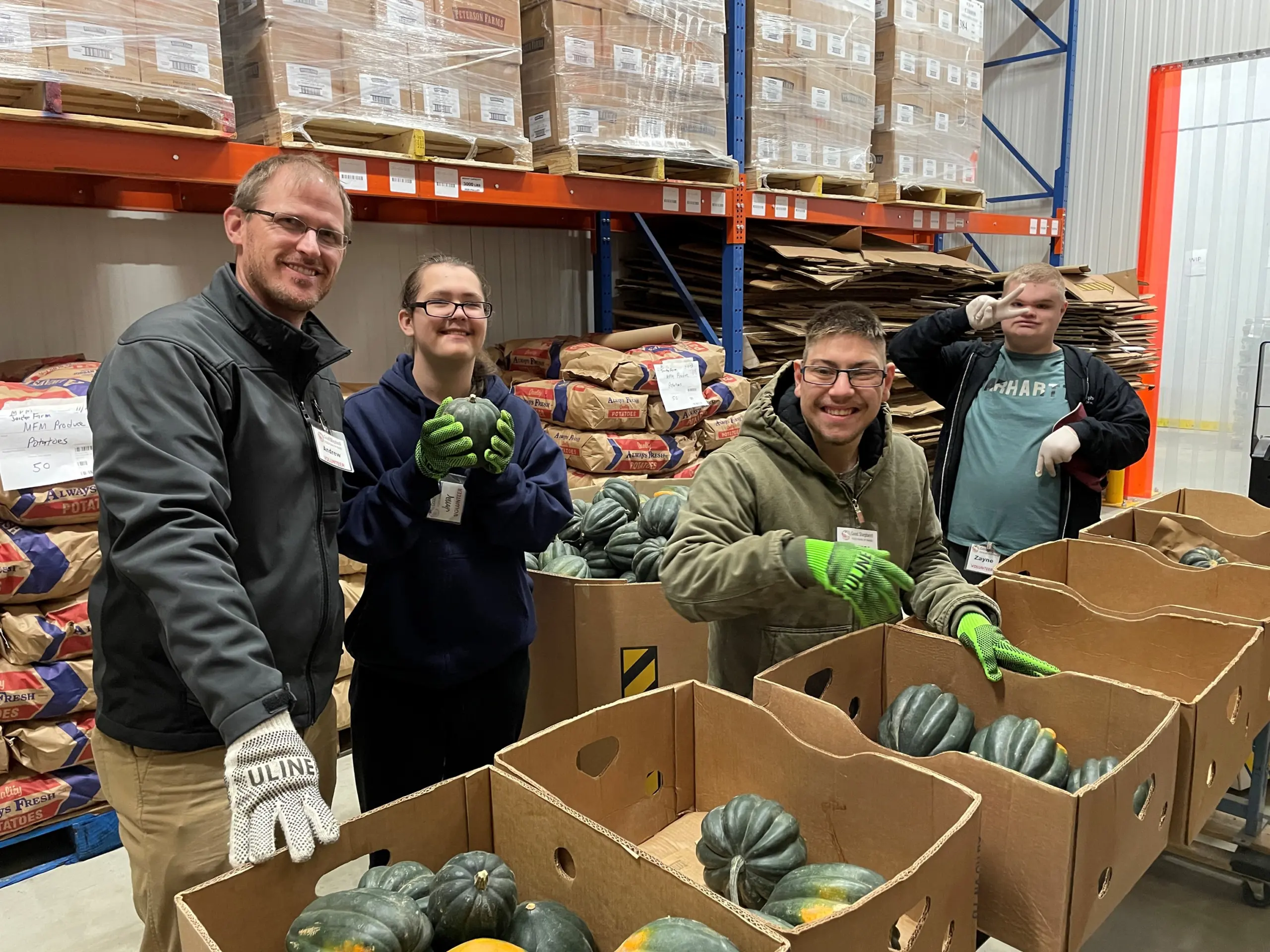 People smiling and posing over boxes of squash.