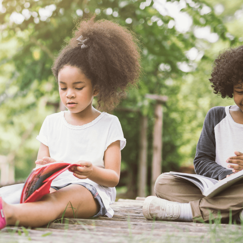 Two children reading books outside