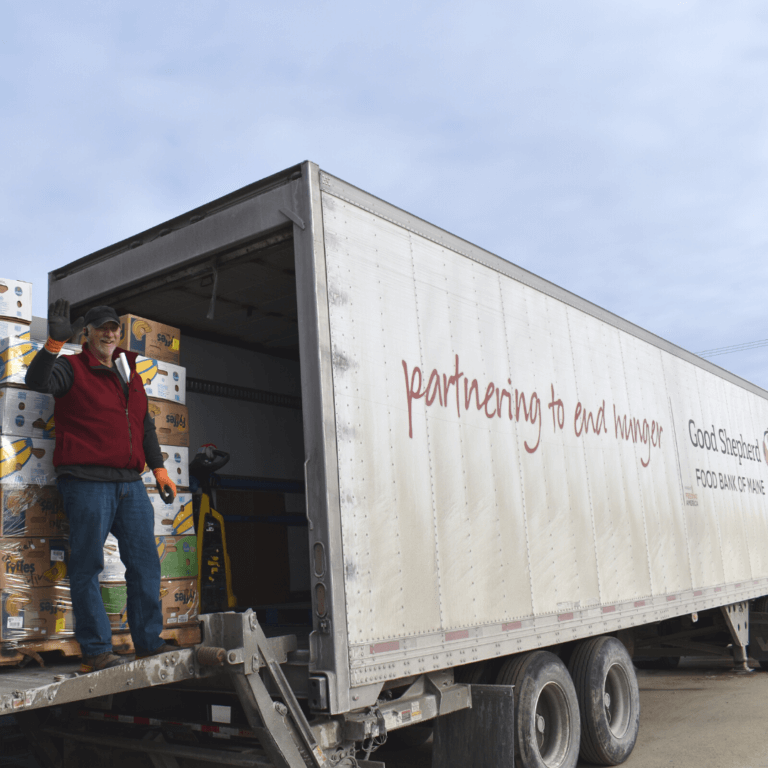 Man standing in the back of a truck with boxes of bananas