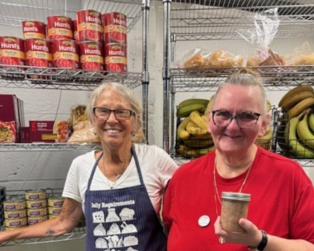 Two woman smiling in front of shelves of food