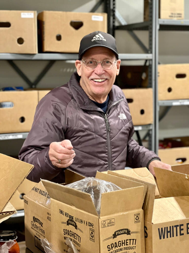 A man smiling while unpacking a box of spaghetti