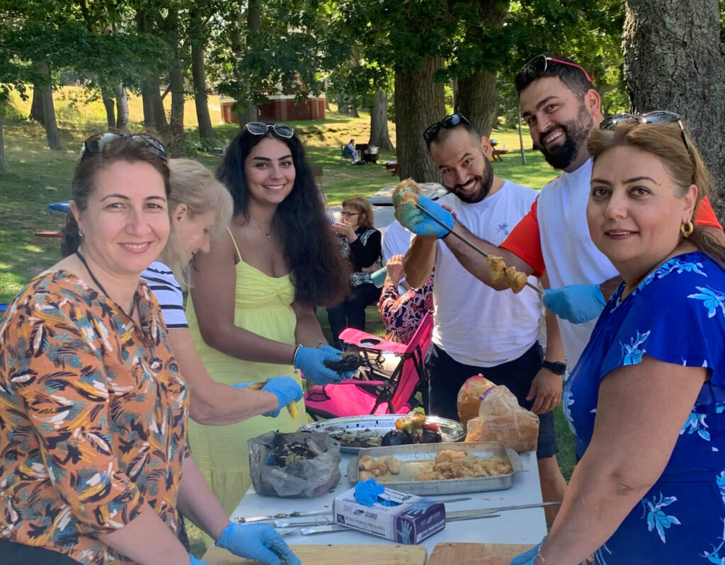 Volunteers surrounding a table outside with different food items. 